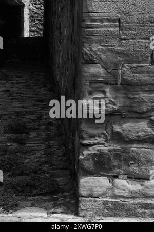 Passaggio di Alley Street: Vecchio muro di pietra che conduce alla luce alla fine del tunnel, dietro l'angolo. Bianco e nero. Foto Stock