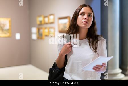 Ragazza focalizzata visitatore, ammira i dipinti nel museo Foto Stock