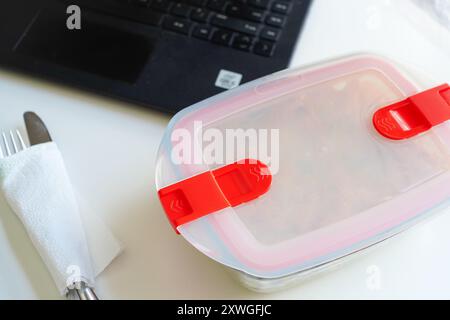 Pranzo con pasta in Tupperware presso il banco dell'ufficio Foto Stock