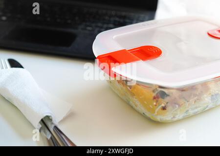 Pranzo con pasta in Tupperware presso il banco dell'ufficio Foto Stock