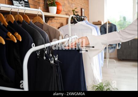 Venditore femminile che prende pantaloni da scaffale nel negozio di abbigliamento maschile, primo piano Foto Stock