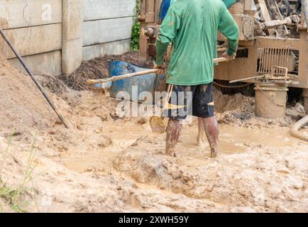 I lavoratori stanno scavando trincee per facilitare il flusso d'acqua. Foratura di un pozzo artesiano Foto Stock