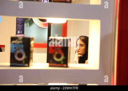 Teheran, Iran. 19 agosto 2024. A Woman Views Products esposti all'undicesima esposizione internazionale di bevande, tè, caffè e industrie affini a Teheran, Iran, 19 agosto 2024. La mostra è iniziata qui lunedì, attirando circa 160 aziende nazionali e straniere per presentare i loro ultimi prodotti, risultati e innovazioni. Crediti: Shadati/Xinhua/Alamy Live News Foto Stock