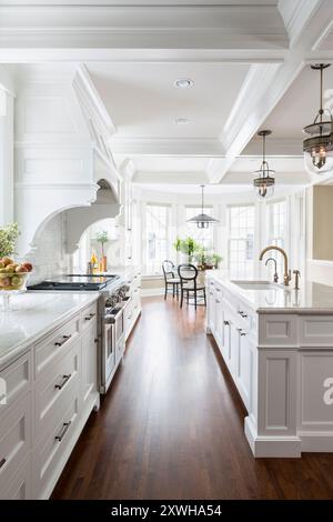 La vista della bellissima cucina bianca mostra il piano cottura e il tavolo da colazione Foto Stock