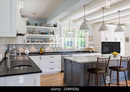 Vista ad angolo della nuova cucina nella vecchia casa, con piastrelle di cemento a motivi geometrici e ripiani in pietra di sapone nera Foto Stock