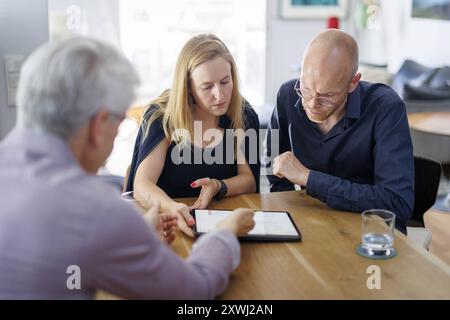 Symbolfoto zum Thema Beratung. Eine junge Frau und ein junger Mann sitzen zu Hause zusammen an einem Tisch und werden beraten. Berlino, 13.08.2024. BER Foto Stock