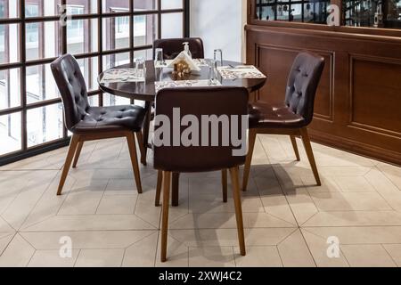 Interno del Cafe' con sedie in legno e tavoli all'interno. Interni e arredi del ristorante. Primo piano elegante design dell'impostazione del piano portapaziente. Interni di un moderno Foto Stock