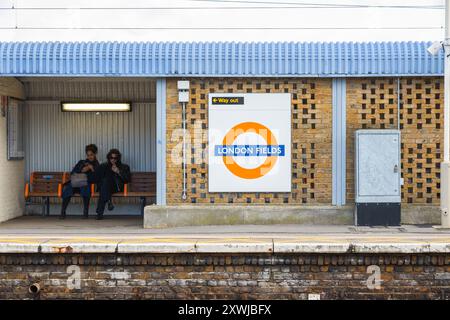 Londra, Regno Unito - 25 gennaio 2024 - passeggeri seduti sulla panchina in attesa al binario della stazione di superficie di London Field Foto Stock