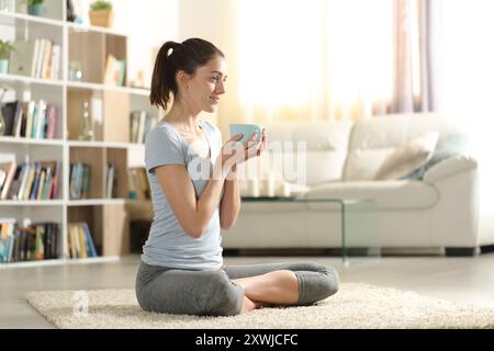 Felice yogi bevendo tè prima di fare esercizio yoga a casa Foto Stock