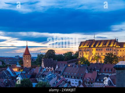 Nürnberger Stadtbild am Abend Blick auf das Tiergärtnertor und den beleuchteten Palas der Kaiserburg in Nürnberg während der Dämmerung. Die historischen Gebäude erstrahlen im Warmen Licht, während der Himmel in Blau- und Orangetönen leuchtet und den Sonnenuntergang über der Stadt einrahmt. Nürnberg Bayern Deutschland *** paesaggio urbano di Norimberga di sera Vista del Tiergärtnertor e del palazzo illuminato del Castello Imperiale di Norimberga al crepuscolo gli edifici storici si illuminano di luce calda, mentre il cielo si illumina di toni blu e arancioni e incornicia il tramonto sulla città di Norimberga Baviera GE Foto Stock