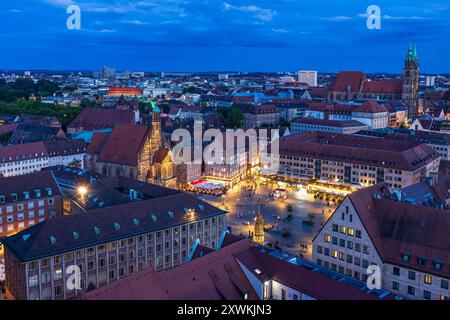 Nürnberger Stadtbild am Abend Blick auf den belebten Hauptmarkt in Nürnberg an einem Samstagabend zur blauen Stunde. Die historischen Gebäude und die Frauenkirche sind in warmes Licht getaucht, während der Markt mit Menschen belebt ist. Die Stadt erstreckt sich im Hintergrund, beleuchtet von den letzten Strahlen des Tages und den Lichtern der Dämmerung. Nürnberg Bayern Deutschland *** paesaggio urbano di Norimberga di sera Vista del mercato principale di Norimberga di sabato sera all'ora blu gli edifici storici e la Frauenkirche sono immersi nella luce calda, mentre il mercato è vivace Foto Stock