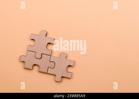Tre pezzi di puzzle in legno collegati su uno sfondo minimalista di pesca, che offrono spazio per il tuo messaggio. Foto Stock