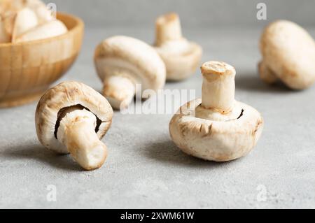 Funghi freschi coltivati crudi in ciotola su sfondo rustico Foto Stock