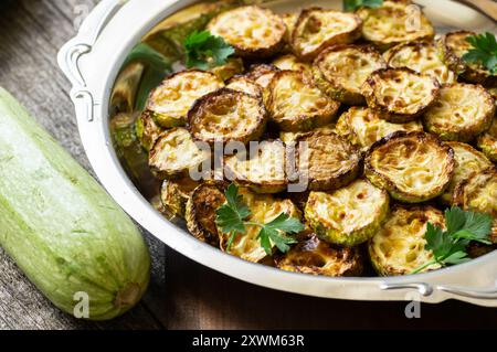 Zucchine fritte con prezzemolo nel piatto su fondo rustico, cibo vegetariano Foto Stock