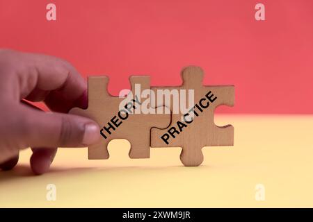 Persona con due pezzi del puzzle etichettati teoria e pratica Foto Stock