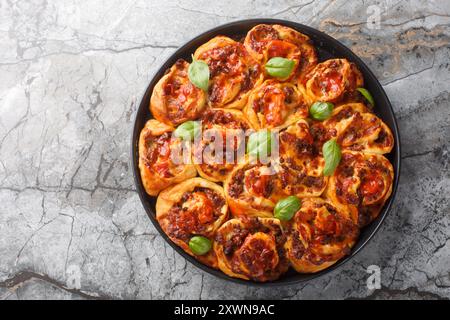 Rustici involtini per pizza ripieni di salsicce italiane, mozzarella, pomodoro e basilico sul piatto bakong sul tavolo. Vista dall'alto orizzontale Foto Stock