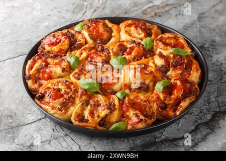 Rustici involtini per pizza ripieni di salsicce italiane, mozzarella, pomodoro e basilico sul piatto bakong sul tavolo. Orizzontale Foto Stock