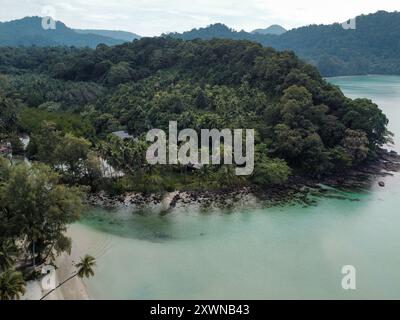 Vista aerea di Koh Kood in una giornata nuvolosa con acqua cristallina, fitta vegetazione e montagne sullo sfondo Foto Stock