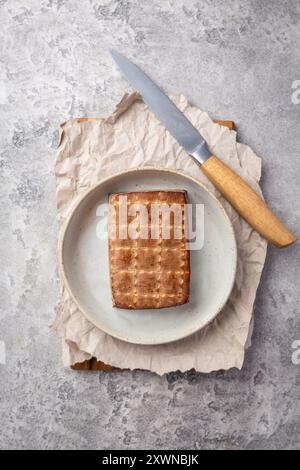 Tofu affumicato biologico sul tavolo della cucina con coltello Foto Stock