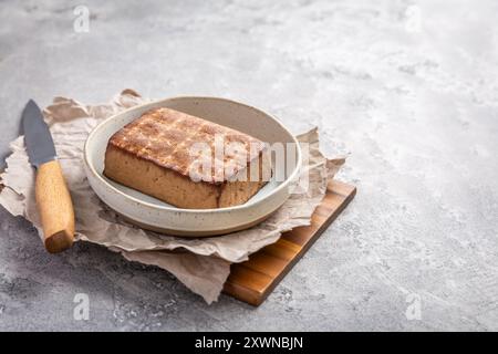 Tofu affumicato biologico sul tavolo della cucina con coltello Foto Stock