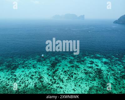 Vista aerea della colorata barriera corallina di Koh Phi Phi Don con Koh Phi Phi le e barche a coda lunga che navigano sullo sfondo Foto Stock