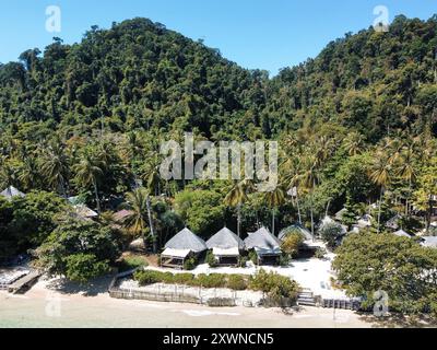 Vista aerea di Ko Ngai con bungalow sulla spiaggia, palme, montagne calcaree e un cielo blu Foto Stock