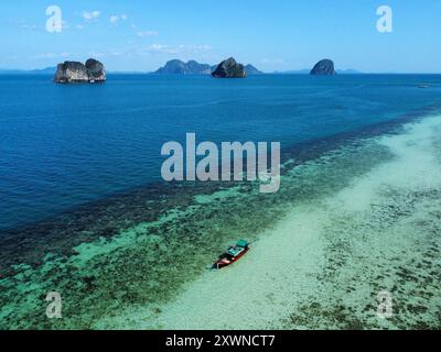 Foto aerea della riva di Ko Ngai con una barca a coda lunga sulle acque turchesi e le isole sullo sfondo Foto Stock