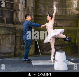 Royal Mile, Edimburgo, Scozia, Regno Unito, 20 agosto 2024. Artisti di strada del Festival Fringe di Edimburgo: Una ballerina australiana professionalmente addestrata, Bianca Carnovalewho si fa chiamare Ballet Busker, intrattiene la folla nonostante si sia infortunata al piede due settimane fa. Coinvolge i membri del pubblico nel suo spettacolo. Crediti: Sally Anderson/Alamy Live News Foto Stock