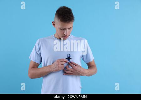 Consapevolezza del cancro alla prostata. Uomo con nastro blu e baffi finti su sfondo colorato Foto Stock