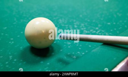 Il giocatore che punta il bersaglio si attacca alla palla bianca sul tavolo da biliardo. Primo piano di una partita da biliardo in azione, sport e attività ricreative Foto Stock