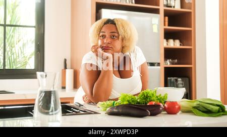 Ritratto donna afroamericana curvy in piedi in cucina con un volto triste Foto Stock