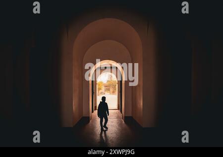 Sagoma di un ragazzo che cammina attraverso un'entrata ad arco all'interno del Pavilion nei giardini Menara, luce e ombra, retroilluminazione, luce e buio, ombra pla Foto Stock