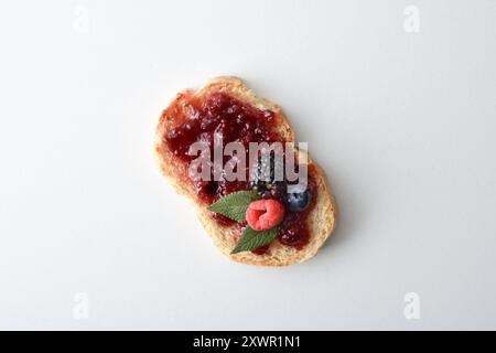 Toast con marmellata di frutta della foresta decorata con frutta isolata su un tavolo bianco. Vista dall'alto. Foto Stock