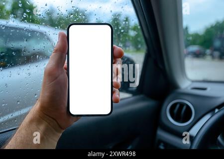 Modello con schermo vuoto per telefono cellulare in auto, conducente maschio che tiene in mano il dispositivo smartphone durante la guida dell'automobile, messa a fuoco selettiva Foto Stock