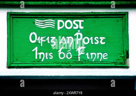 Post office sign in gaelico irlandese lingua dipinta a mano su isola di Inishbofin al largo della costa della contea di Galway in Irlanda occidentale Foto Stock