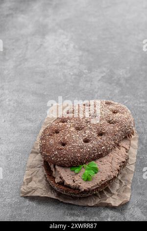 Pate di carne di fegato spalmato sul pane di segale su sfondo grigio Foto Stock