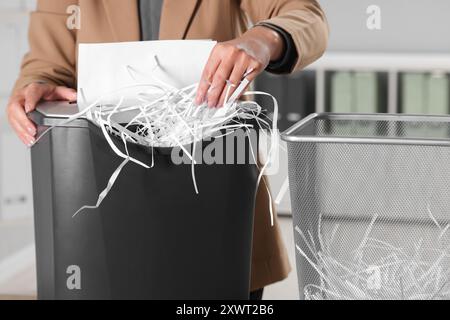 Donna che distrugge fogli di carta con trituratore in ufficio, primo piano Foto Stock