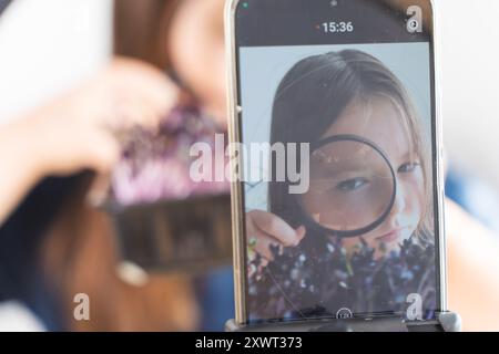 Una bambina pre-adolescente scrive un video blog o vlog sul suo cellulare su microgreen coltivati. Messa a fuoco selezionata. Foto di alta qualità Foto Stock