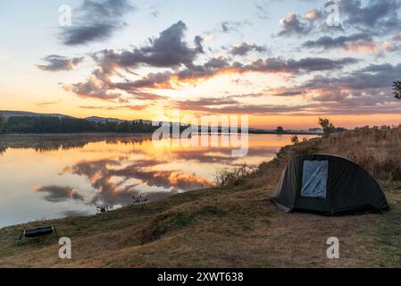 Le avventure di pesca, la pesca alla carpa. Il pescatore, al tramonto, è la pesca con carp fishing tecnica. Campeggio in riva al lago. Foto Stock