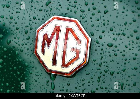 Logo e logo vintage classico MG MGB cromati sul cofano dell'auto con gocce di pioggia Foto Stock