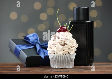 Buona festa del papà. Cupcake, confezione regalo e profumo sul tavolo di legno contro luci sfocate e primo piano Foto Stock