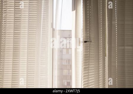 Finestra aperta con persiane bianche e tende che si affacciano su una casa vicina in Ucraina, vista dalla finestra dell'appartamento Foto Stock