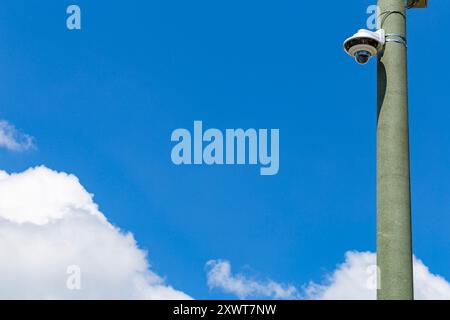 Telecamera di sicurezza su un palo luminoso sulla strada. Telecamera di sicurezza e video urbano di fronte al cielo blu. Telecamere di videosorveglianza cctv esterne. Foto Stock