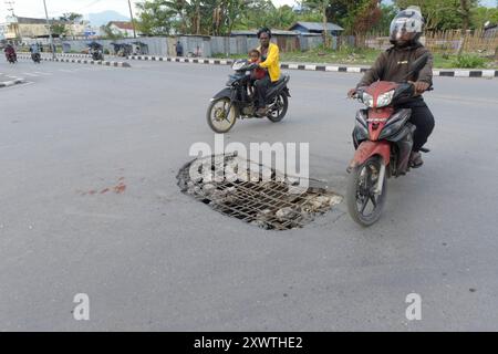 Wer in Wamena von der Hauptstraße in diese Seitenstraße abbiegt, muss aufpassen, keinen Unfall zu bauen. Unter dem Asphalt verläuft ein Abwasserkanal und die Teerdecke ist an einer stelle durchbrochen. *** Chiunque chiuda la strada principale in questa strada laterale a Wamena deve fare attenzione a non causare un incidente Una fogna corre sotto l'asfalto e la superficie del catrame è rotta in un posto Foto Stock