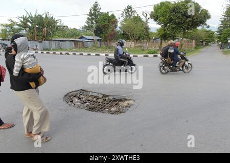 Wer in Wamena von der Hauptstraße in diese Seitenstraße abbiegt, muss aufpassen, keinen Unfall zu bauen. Unter dem Asphalt verläuft ein Abwasserkanal und die Teerdecke ist an einer stelle durchbrochen. *** Chiunque chiuda la strada principale in questa strada laterale a Wamena deve fare attenzione a non causare un incidente Una fogna corre sotto l'asfalto e la superficie del catrame è rotta in un posto Foto Stock