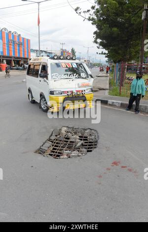 Wer in Wamena von der Hauptstraße in diese Seitenstraße abbiegt, muss aufpassen, keinen Unfall zu bauen. Unter dem Asphalt verläuft ein Abwasserkanal und die Teerdecke ist an einer stelle durchbrochen. DAS gleiche gilt für den Gehweg, wo einzelne Betonplatten verschoben sind. *** Chiunque chiuda la strada principale in questa strada laterale a Wamena deve fare attenzione a non causare incidenti Una fogna corre sotto l'asfalto e la superficie del catrame è rotta in un posto lo stesso vale per il marciapiede, dove le singole lastre di cemento si sono spostate Foto Stock