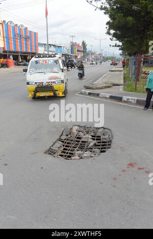 Wer in Wamena von der Hauptstraße in diese Seitenstraße abbiegt, muss aufpassen, keinen Unfall zu bauen. Unter dem Asphalt verläuft ein Abwasserkanal und die Teerdecke ist an einer stelle durchbrochen. DAS gleiche gilt für den Gehweg, wo einzelne Betonplatten verschoben sind. *** Chiunque chiuda la strada principale in questa strada laterale a Wamena deve fare attenzione a non causare incidenti Una fogna corre sotto l'asfalto e la superficie del catrame è rotta in un posto lo stesso vale per il marciapiede, dove le singole lastre di cemento si sono spostate Foto Stock