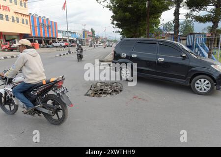 Wer in Wamena von der Hauptstraße in diese Seitenstraße abbiegt, muss aufpassen, keinen Unfall zu bauen. Unter dem Asphalt verläuft ein Abwasserkanal und die Teerdecke ist an einer stelle durchbrochen. *** Chiunque chiuda la strada principale in questa strada laterale a Wamena deve fare attenzione a non causare un incidente Una fogna corre sotto l'asfalto e la superficie del catrame è rotta in un posto Foto Stock