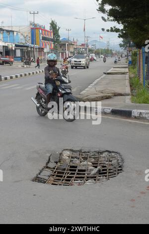 Wer in Wamena von der Hauptstraße in diese Seitenstraße abbiegt, muss aufpassen, keinen Unfall zu bauen. Unter dem Asphalt verläuft ein Abwasserkanal und die Teerdecke ist an einer stelle durchbrochen. DAS gleiche gilt für den Gehweg, wo einzelne Betonplatten verschoben sind. *** Chiunque chiuda la strada principale in questa strada laterale a Wamena deve fare attenzione a non causare incidenti Una fogna corre sotto l'asfalto e la superficie del catrame è rotta in un posto lo stesso vale per il marciapiede, dove le singole lastre di cemento si sono spostate Foto Stock