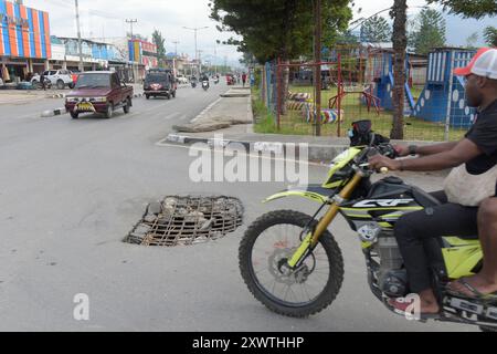 Wer in Wamena von der Hauptstraße in diese Seitenstraße abbiegt, muss aufpassen, keinen Unfall zu bauen. Unter dem Asphalt verläuft ein Abwasserkanal und die Teerdecke ist an einer stelle durchbrochen. DAS gleiche gilt für den Gehweg, wo einzelne Betonplatten verschoben sind. *** Chiunque chiuda la strada principale in questa strada laterale a Wamena deve fare attenzione a non causare incidenti Una fogna corre sotto l'asfalto e la superficie del catrame è rotta in un posto lo stesso vale per il marciapiede, dove le singole lastre di cemento si sono spostate Foto Stock